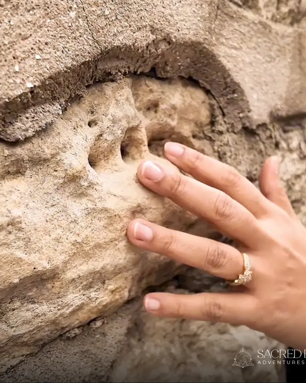 A hand resting on carved stone, from Sacred Earth Adventures’ own photography