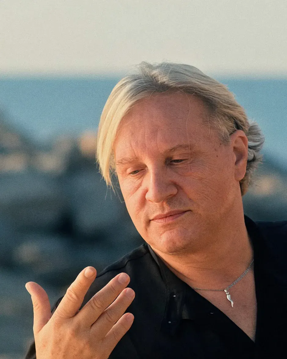 Gabriel at golden hour, in a black shirt, one hand open in front of him